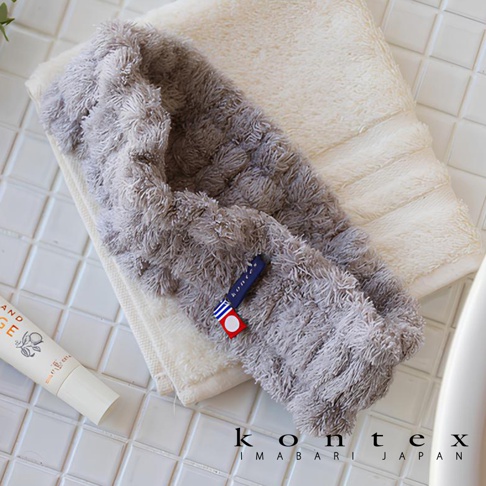 平口浴裙和抗菌髮帶禮盒，浴裙為灰色蓬鬆毛巾材質，髮帶為白色毛巾材質，上面裝飾有藍底白字及紅白條紋的品牌標籤。