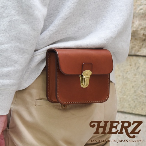 經典棕色皮革腰包，以手工縫製，搭配金色搭扣，可繫於腰間，風格簡約實用。