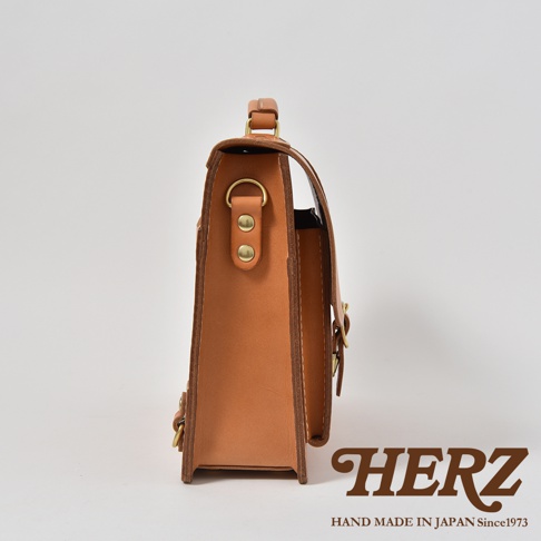 職人手作皮革三用單扣商務後背包，側邊視角，淺棕色皮革，搭配金色單扣及鉚釘，簡約俐落的設計。