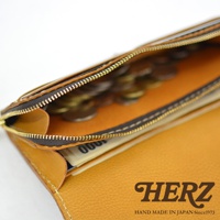 職人手作皮革長夾，特寫打開的拉鍊零錢袋，內有硬幣，並可見部分紙鈔。整體為芥末黃色皮革，搭配深棕色拉鍊與金色拉頭，車縫線細緻。