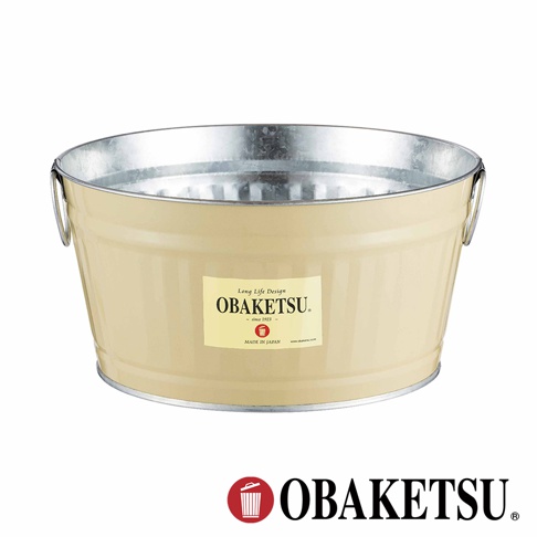 OBAKETSU 奶油色圓筒形狀金屬水桶，帶有銀色提把，桶身貼有品牌標籤，底部印有「MADE IN JAPAN」字樣，下方是 OBAKETSU 品牌標誌。