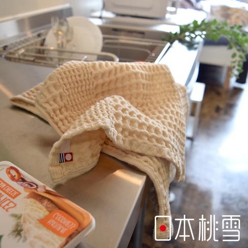 米白色今治鬆餅方巾，具有立體格紋織法，柔軟親膚，角落縫有紅藍色標籤。