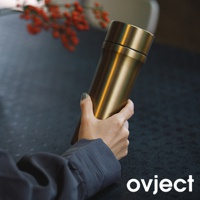 手持一只金色金屬材質的三用保溫瓶，瓶身呈現光滑的圓柱狀，上方有旋轉式瓶蓋。