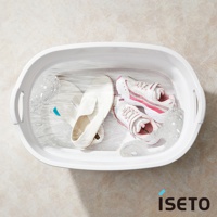 白色伸縮浴盆內有水，盆中放著一雙白色平底鞋和一雙粉白色運動鞋，有部分氣泡。