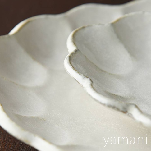 兩個白色陶瓷花型橢圓料理盤，表面帶有粉引釉料的紋理，邊緣為不規則的六邊形，營造出樸實的手工質感。