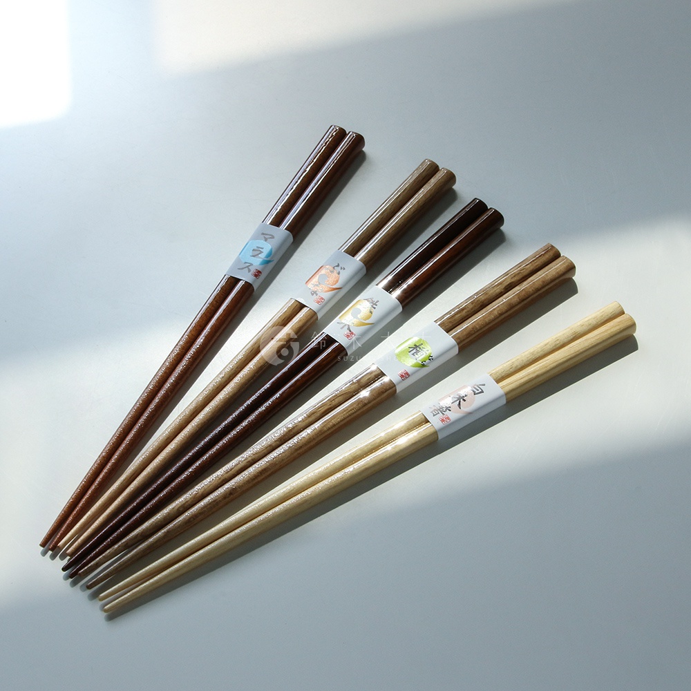 五雙天然原色木筷，顏色從深棕色漸變至淺木色，部分筷子帶有裝飾性紙帶，表面光滑。