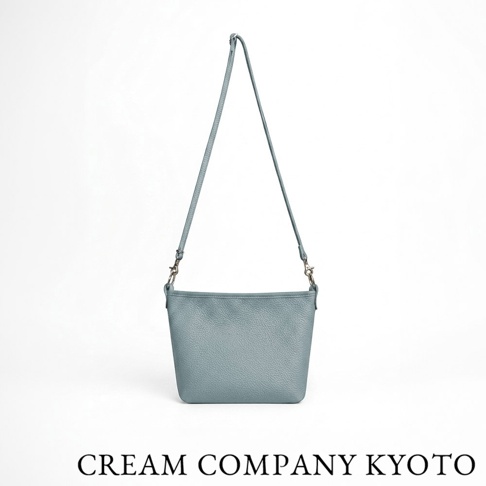 CREAM COMPANY KYOTO 淺藍色手工隨身側背包，採用柔軟紋理牛皮革製成，包身簡約輕巧，配有可拆卸的細長肩帶，整體設計俐落實用。