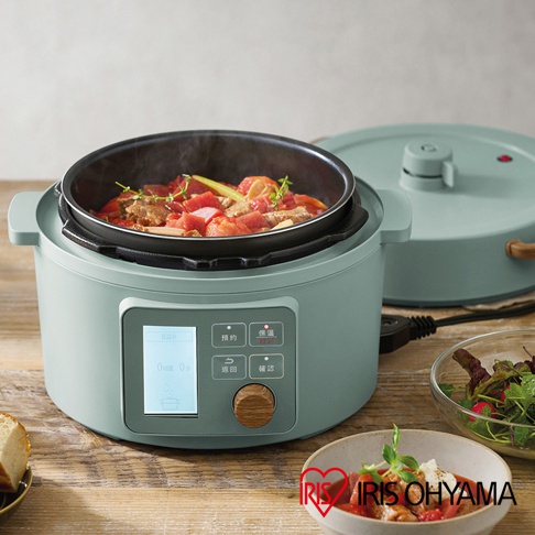 淺綠色電子壓力鍋，內含燉煮中的肉塊與番茄，配有數位顯示螢幕與木紋旋鈕。