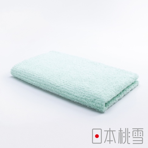 一條淺綠色的今治細絨毛巾，材質柔軟，表面有細密的絨毛，折疊平放在白色背景上。
