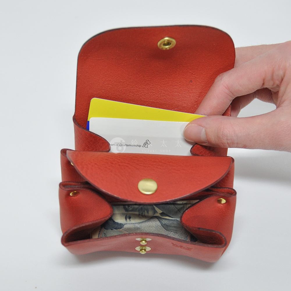 紅色皮革三層收納零錢包，可放入信用卡和紙鈔，包體有金色按扣設計，材質為皮革。