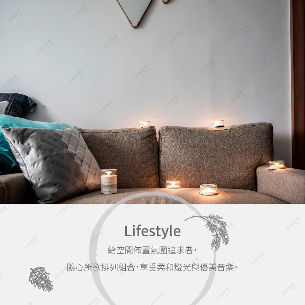 一個白色的圓柱形音響，上方有燈光，擺放在沙發上，周圍有數個透明玻璃杯裡裝有燭光，營造溫馨氛圍。