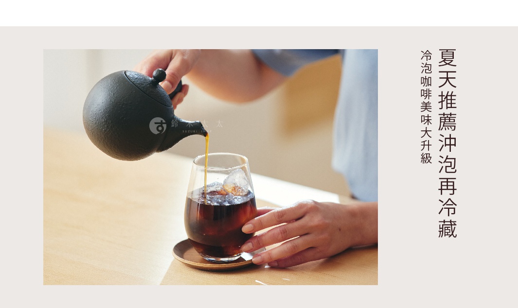 一只黑色常滑燒咖啡急須茶壺，壺嘴傾斜，正將咖啡倒入裝有冰塊的玻璃杯中。