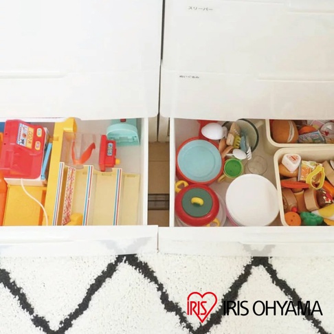 白色四層收納櫃的抽屜內，分別收納著各式兒童玩具，包含收銀機、玩具餐具、扮家家酒廚具組及積木等，色彩繽紛。