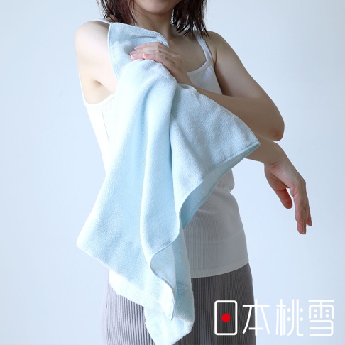 一位女性手持一條淺藍色迷你浴巾，浴巾呈現厚實的質地。