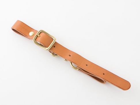 職人手作皮革背包用胸前扣帶，寬2.4公分，材質為棕色皮革，配有黃銅色金屬扣環、鉚釘及D型環。