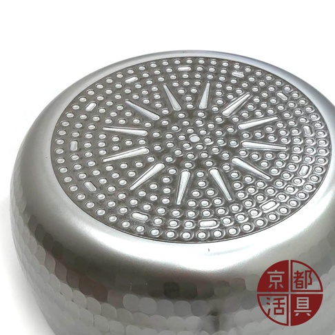 厚板鋁製雪平鍋底部，呈現放射狀網點紋理，鍋身為銀色金屬材質，帶有錘紋質感。