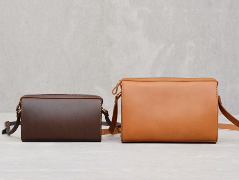 兩款職人手作皮革極簡風拉鍊單肩包，一款為深棕色，另一款為淺棕色，均為方形設計，配有可調節的皮革肩帶和金屬拉鍊。