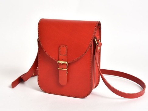 紅色皮革迷你翻蓋單肩包，配有皮帶和黃銅搭扣。