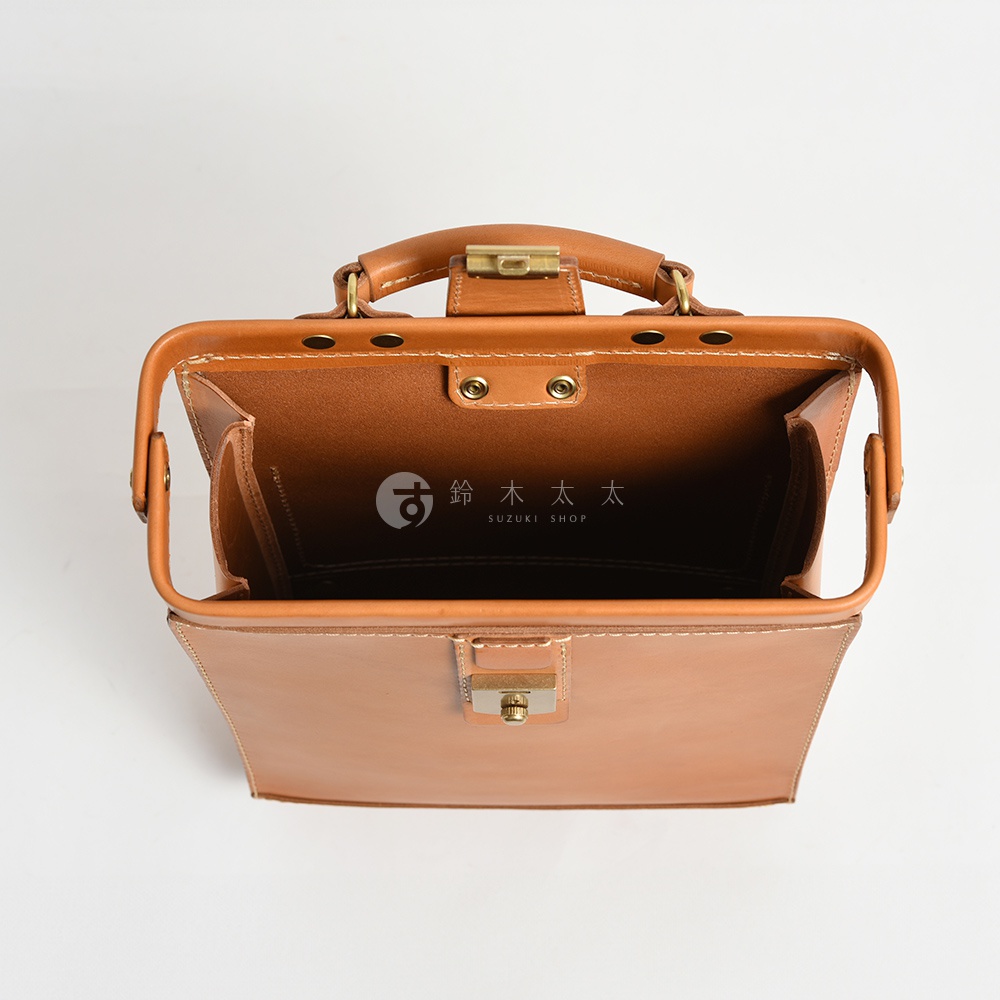 職人手作皮革杜勒斯商務後背包，這款棕色皮革後背包的頂部視圖，展現其經典的醫生包造型，配有頂部提把、金屬鎖扣及細緻車縫線。