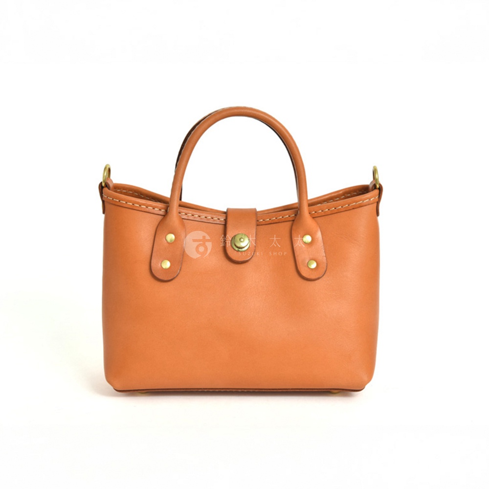 棕色皮革迷你托特包，配有圓形提把、金色金屬釦及鉚釘裝飾，簡約設計。