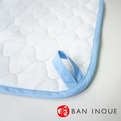 白色兩層蚊帳棉織吸水墊，表面有蜂窩狀縫線，附有淺藍色織帶掛環，並以淺藍色織邊包覆。