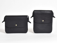 兩款黑色皮革橫式隨行袋，設計簡約，附有翻蓋和金色按扣。