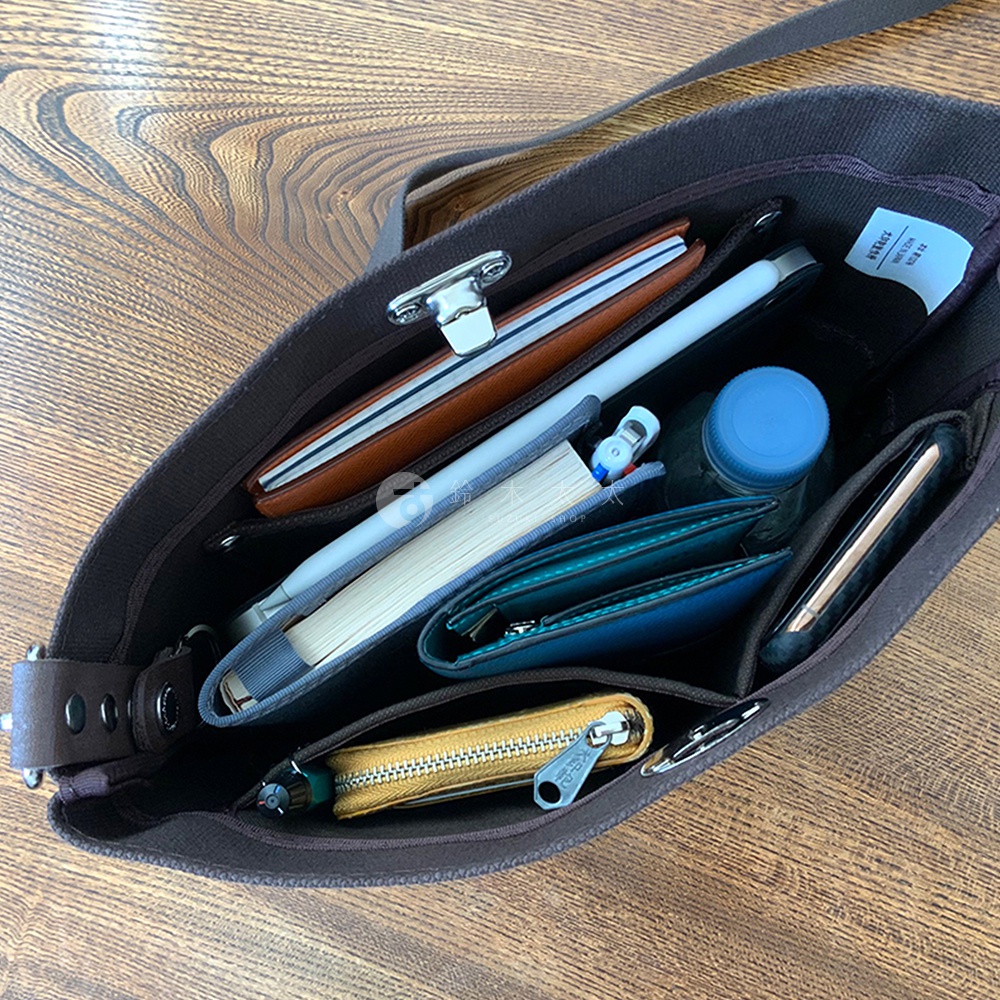 深棕色純棉帆布迷你側背包內部，裝有棕色皮夾、白色觸控筆、藍色水瓶、綠松石色錢包、手機及黃色拉鍊零錢包。