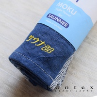 SAUNNER MOKU 薄輕長精繡桑拿浴巾，深藍色，材質為精緻織物，表面有黃色日文「サウナ部」刺繡，邊緣有白色縫線。