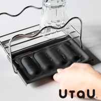 不鏽鋼多功能萬用瀝水支架，設有黑色集水盤，上方置有一個玻璃杯，手部正將集水盤拉出。