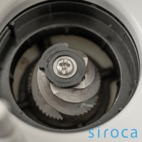 SC-C2510 石臼式全自動研磨咖啡機的研磨組件，包含銀色金屬刀盤和黑色塑膠固定環，上方有螺絲固定。