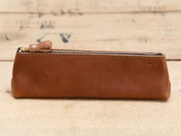 職人手作的棕色皮革三角收納筆袋，配有金色拉鍊和皮革拉環，表面有細微紋理，右側印有「Organ」字樣。