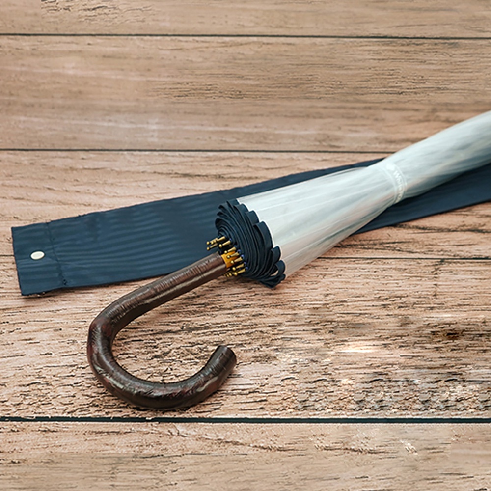 職人高級樺木透明傘，傘面為透明材質，傘骨及傘柄為深棕色樺木，搭配深藍色傘套。