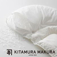 白色布質枕頭，拉鍊部分敞開，露出內部填充的許多透明小顆粒，部分顆粒散落在枕頭外。