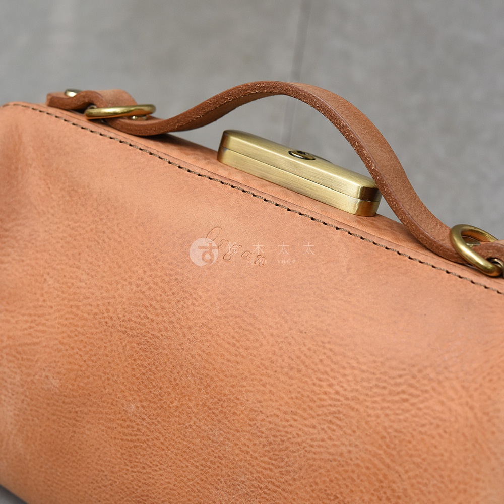 日本HERZ職人手作皮革Organ鎖孔式大開口肩背包M-7，特寫箱型鎖與皮革提把，包包呈現自然光澤與壓印Logo