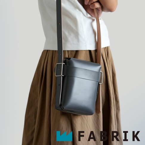 FABRIK 黑色皮革迷你斜背包，搭配棕色皮革背帶，展示於穿著棕色長裙的模特兒身上
