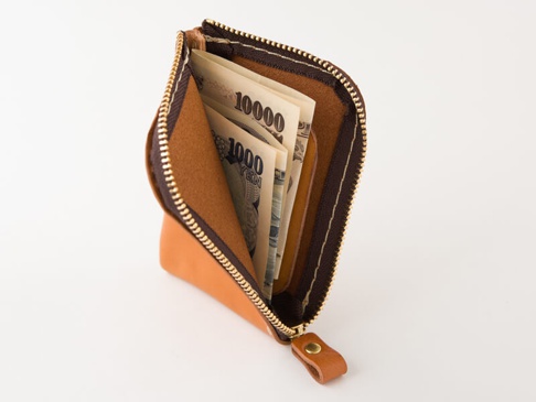 職人手作的卡其色皮革迷你錢包，拉鍊部分為深棕色，內部有日圓紙鈔。