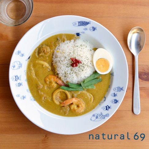 一個飾有藍色魚圖案的白色陶瓷義大利麵盤，盛有咖哩飯、蝦仁、花枝圈、水煮蛋和四季豆。