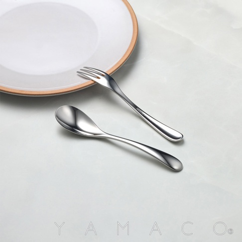 一組不鏽鋼點心叉匙，叉子上有品牌標示，背景為白色盤子和淺色桌面