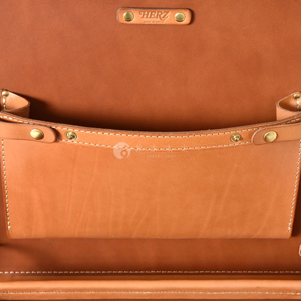 職人手作皮革英倫風便攜手提行李箱 TR-1，特寫內部，展示鞣製皮革的自然紋理與縫線細節，包含一個較淺的收納袋，上方有品牌烙印。