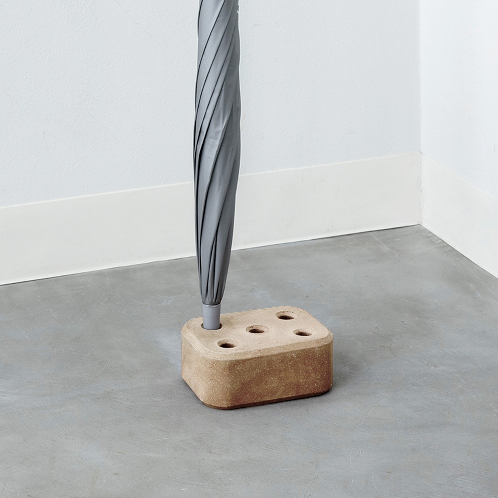 淺褐色磚塊造型傘架，有五個圓形置傘孔，上方放置一支灰色折疊傘。