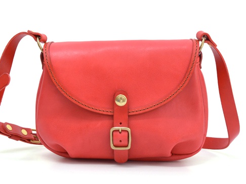 紅色皮革馬鞍包，帶有皮帶扣和金屬搭扣，適合休閒旅行。