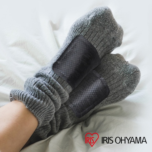 一雙灰色針織貼襪式暖暖包，每隻腳的暖暖包貼在襪子的外側，表面有網格紋路。