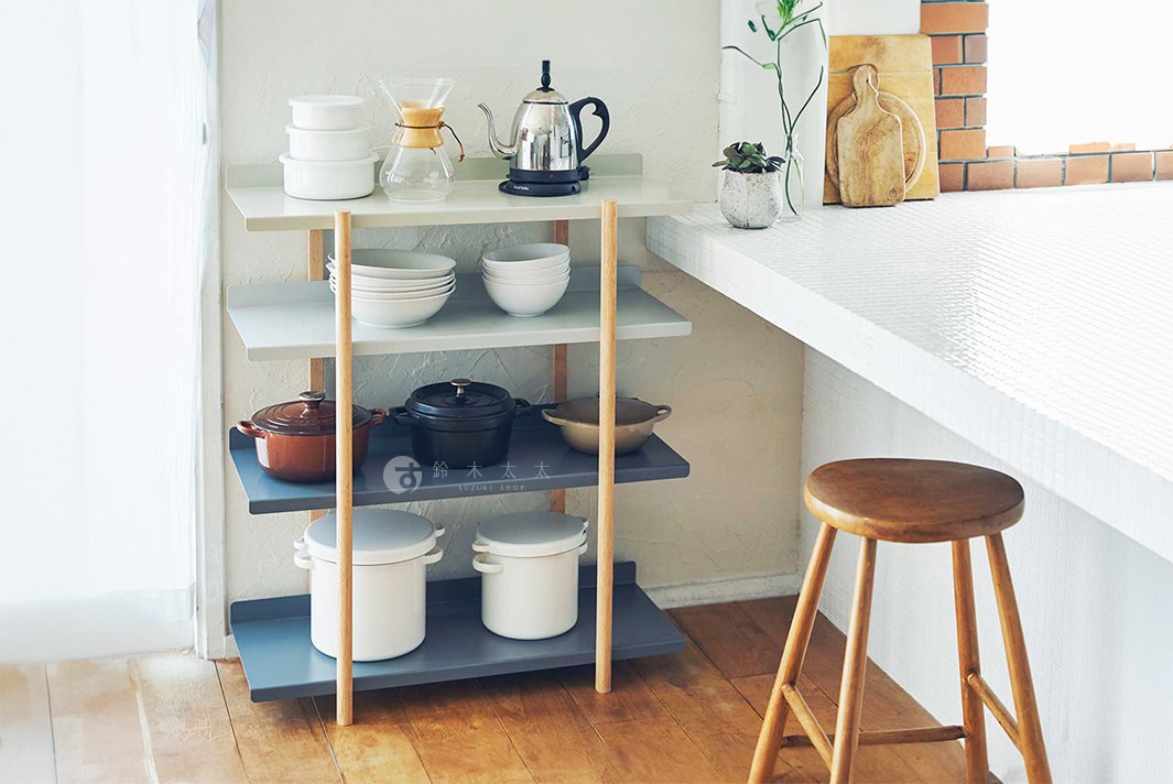 MARGE SHELF 4 四層置物收納架，淺灰色與深藍色層板，搭配原木支架，上方擺放白色餐具、玻璃咖啡壺、金屬茶壺、灰色鑄鐵鍋、白色鍋具等廚房用品。