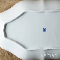 淡青白釉美濃燒輪花長盤，盤底中央有藍色小花圖案，盤緣呈波浪狀，材質為陶瓷。