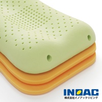 淺綠色記憶棉枕頭堆疊在兩層橘色海綿墊上，枕頭表面佈滿圓形透氣孔，呈現波浪狀凹槽設計。