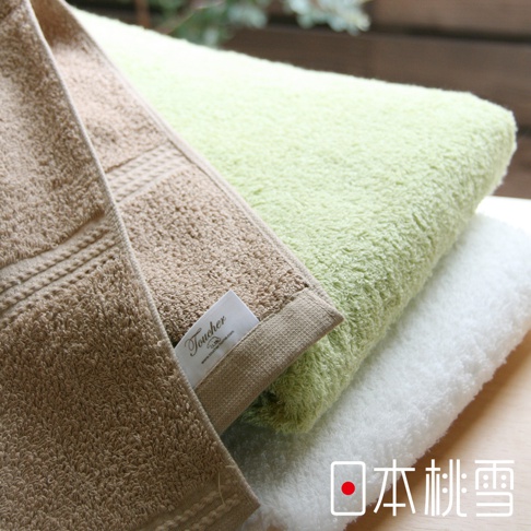 三條居家浴巾疊放，分別為卡其色、淺綠色和白色。卡其色浴巾有著精緻的編織邊緣和品牌標籤。