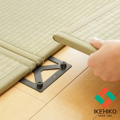 藺草榻榻米專用連結器，黑色塑膠材質，呈三角形結構，用於固定兩塊米色藺草榻榻米。