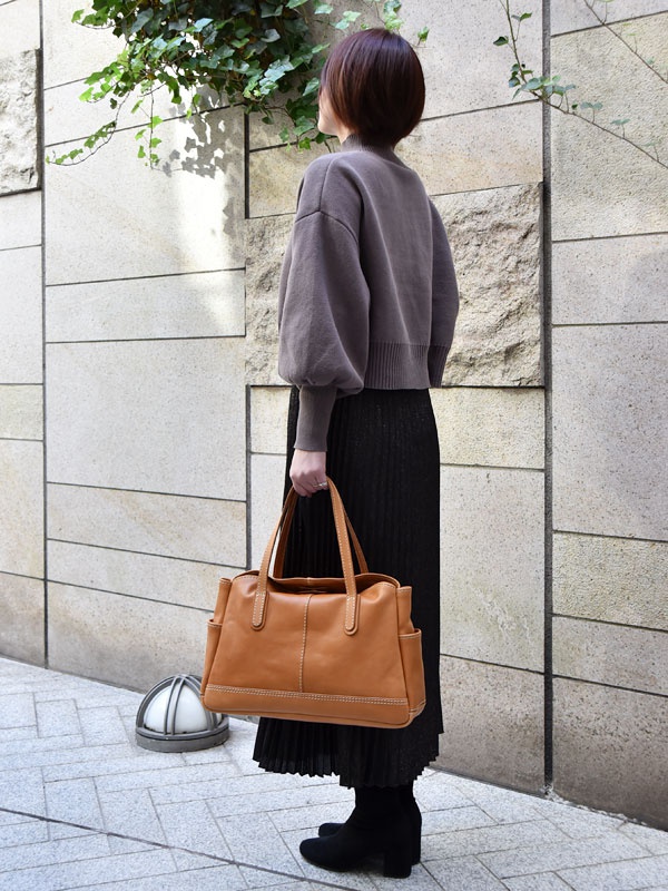 棕色皮革橫式肩背托特包，帶有對比色縫線，頂部有提把，兩側有口袋。