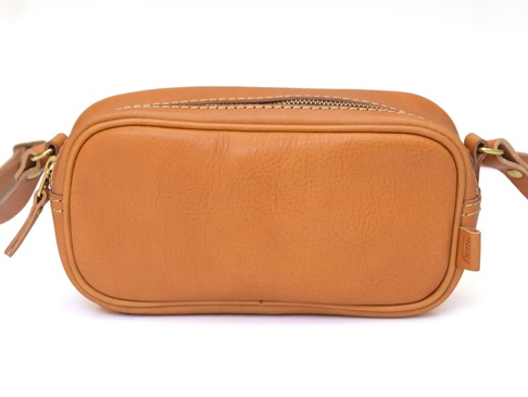 職人手作皮革隨身單肩小包，採用棕褐色皮革製成，包身方正，頂部有金色拉鍊，皮革表面有自然紋理，側面有品牌標籤。