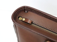 職人手作皮革兩用商務托特包 (T-7) 的特寫，展示了咖啡色皮革材質、精緻的縫線以及金色金屬拉鍊與拉頭。